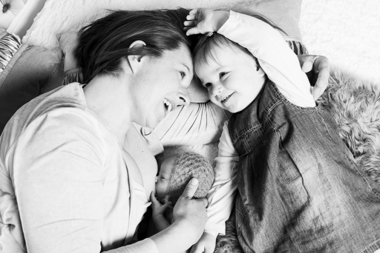 Mama mit Tochter und Baby beim Stillen im Bett