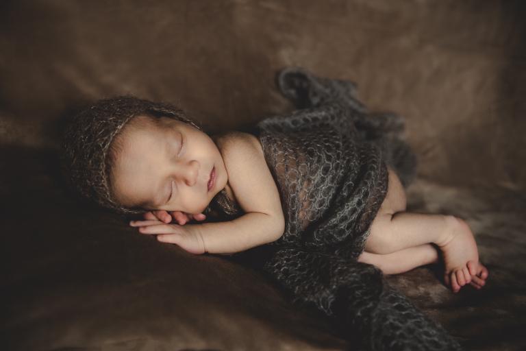 schlafendes neugeborenes Baby mit gestrickter Mütze und Decke
