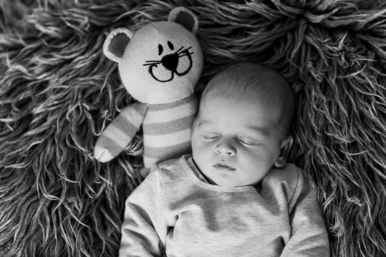 Babyfoto in S/W mit Kuscheltier schlafend