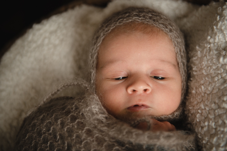 Neugeborenes Baby im Babykorb mit Decke und Mütze