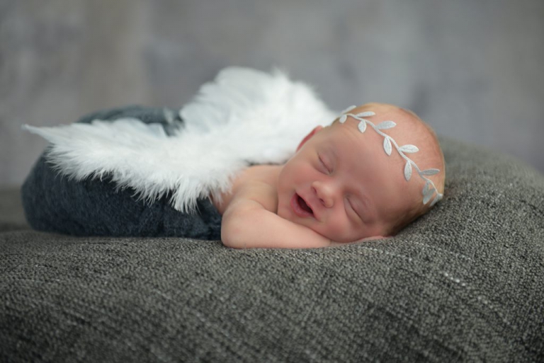 schlafendes lachendes baby mit Engelflügel und Krone
