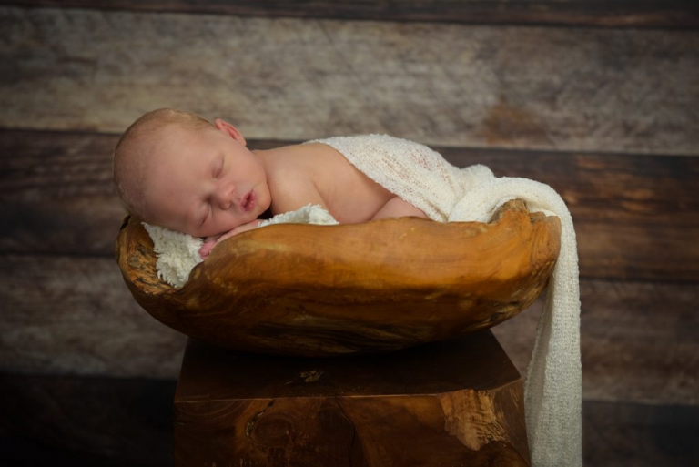Baby schlafend in Holzkorb mit weisses Tuch bedeckt