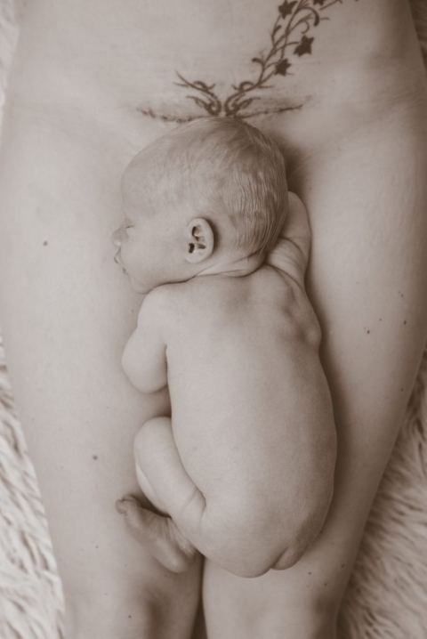 Neugeborenes nacktes Baby liegt am Unterleib ihre nackte Muter
